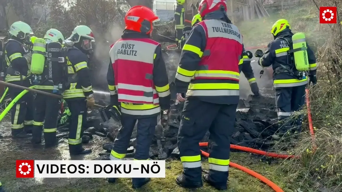 Feuerwehrleute in Schutzkleidung arbeiten an einem Brandort. Ein Feuerwehrmann heißt Rust, ein anderer Tank Tullerbach. Rauch und Trümmer umgeben sie.