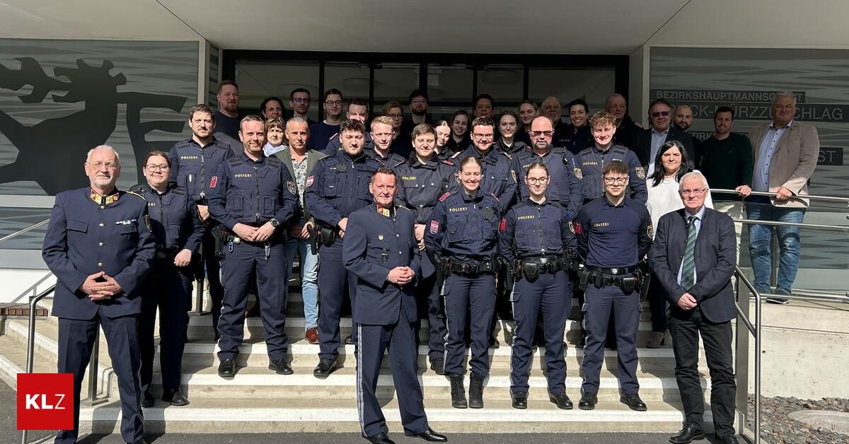 Eine Gruppe uniformierter Polizeibeamter steht auf Stufen vor einem Gebäude und lächelt für ein Foto.
