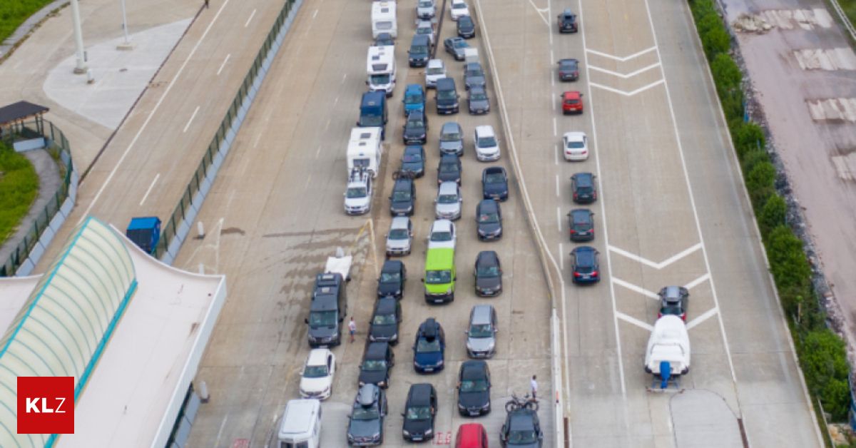 Eine Luftaufnahme eines Parkplatzes, auf dem mehrere Fahrzeuge, einschließlich Autos, Vans und SUVs, in ordentlichen Reihen geparkt sind. Einige Leute gehen herum, und es gibt Barrieren auf der linken Seite.