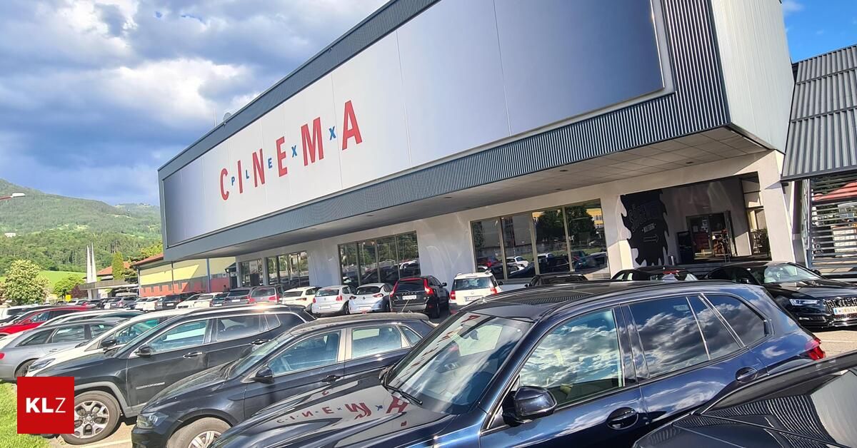 Kino CinemaX mit vielen parkenden Autos davor. Der Himmel ist teilweise bewölkt.