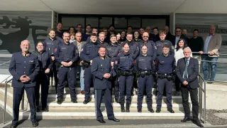 Eine Gruppe von Polizeibeamten posiert in Uniform vor einem Gebäude für ein Foto.