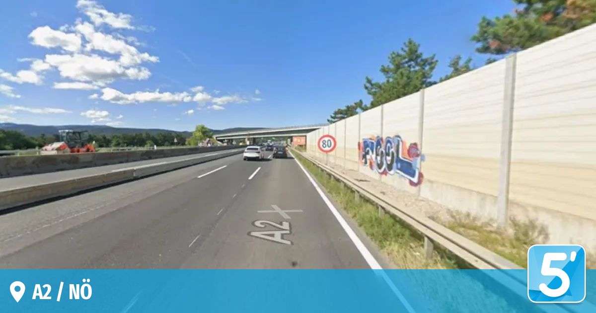 Eine Autobahn mit fahrenden Autos an einem Verkehrsschild, das eine Geschwindigkeitsbegrenzung von 80 km/h anzeigt. Die Straße hat weiße und gelbe Markierungen. Die Seite hat eine Betonbarriere mit Graffiti.