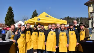 Eine Gruppe von Männern in gelben Schürzen mit einem Logo posieren für ein Foto vor einem gelben Zelt.