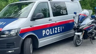 Ein Polizeivan mit 'POLIZEI' in Weiß auf der Seite und einem Motorrad, das daneben geparkt ist.