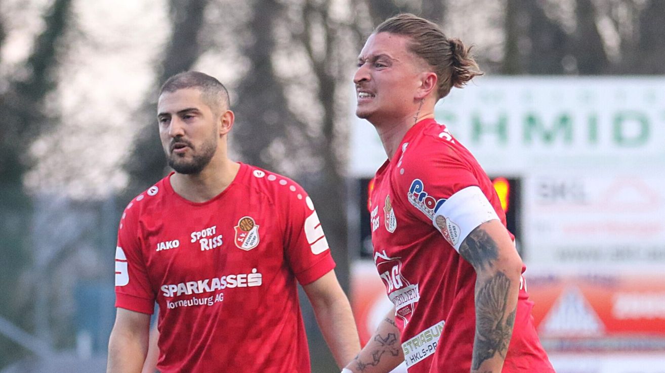 Zwei Fußballspieler in roten Trikots mit Tätowierungen an den Armen, einer lächelt und der andere sieht ernst aus.
