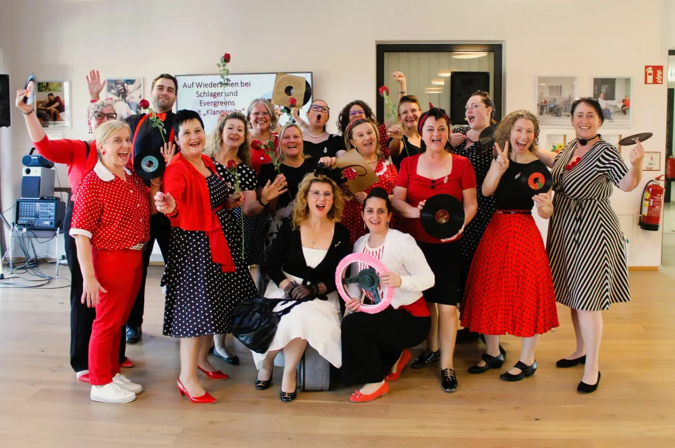 A group of people dressed in 1950s style, posing for a photo. They are holding roses and vinyl records.