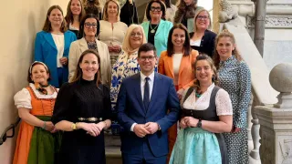 Eine Gruppe von Frauen und ein Mann steht auf den Stufen und trägt formelle Kleidung, Brillen und Accessoires. Sie lächeln und scheinen für ein Foto zu posieren.