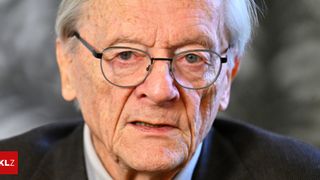 Ein älterer Mann mit weißen Haaren und Brille sieht mit ernster Miene nach vorne.