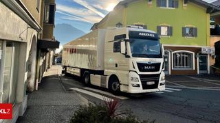 Ein weißer MAN-LKW ist am Straßenrand geparkt, mit einem Berg in der Ferne.