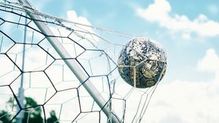 Ein Fußball mit aufwendigen Mustern ist in einem Netz gefangen, vor einem blauen Himmel mit verstreuten Wolken.