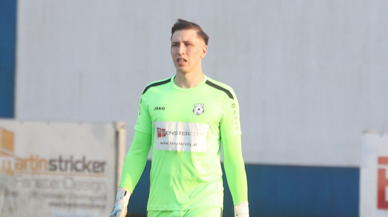 A soccer player in a neon green uniform with 'Jako' and a soccer ball logo on the chest is walking on a field.