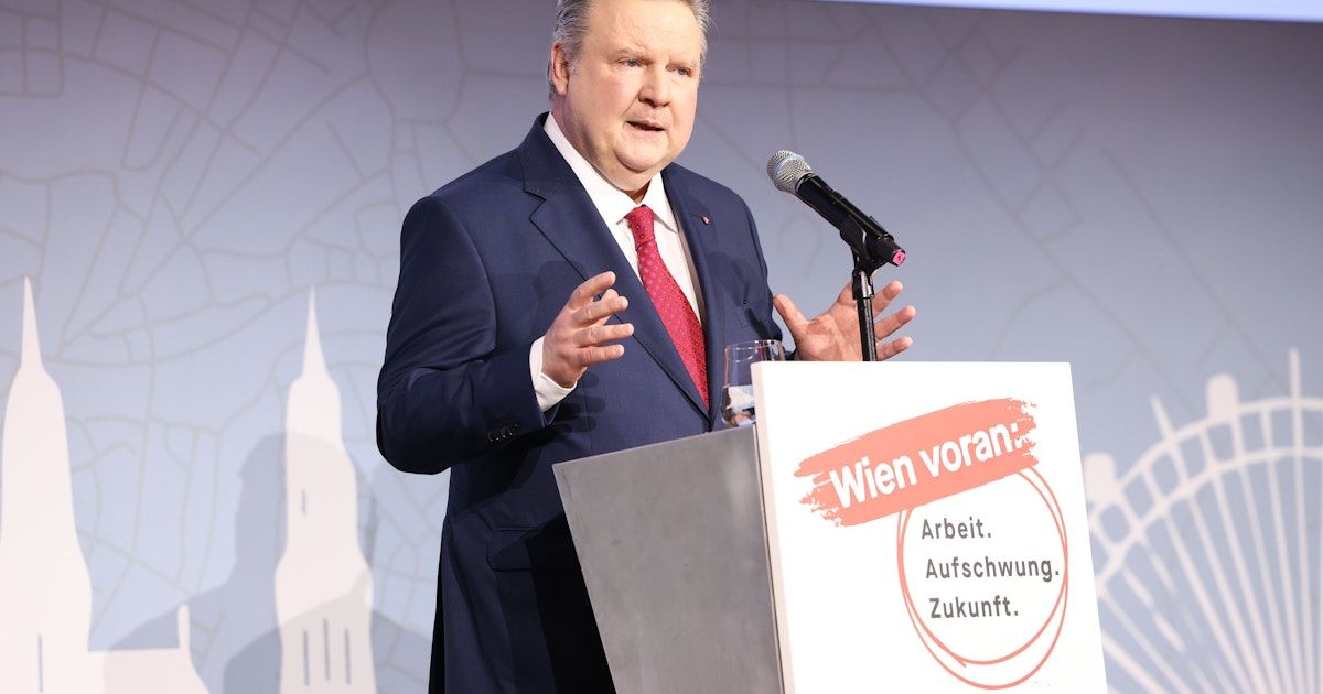 Ein Mann in Anzug steht an einem Podium mit Mikrofon und gestikuliert mit den Händen. Dahinter steht ein Schild mit der Aufschrift 'Wien voran: Arbeit. Aufschwung. Zukunft.' Ein Glas Wasser steht auf dem Podium.
