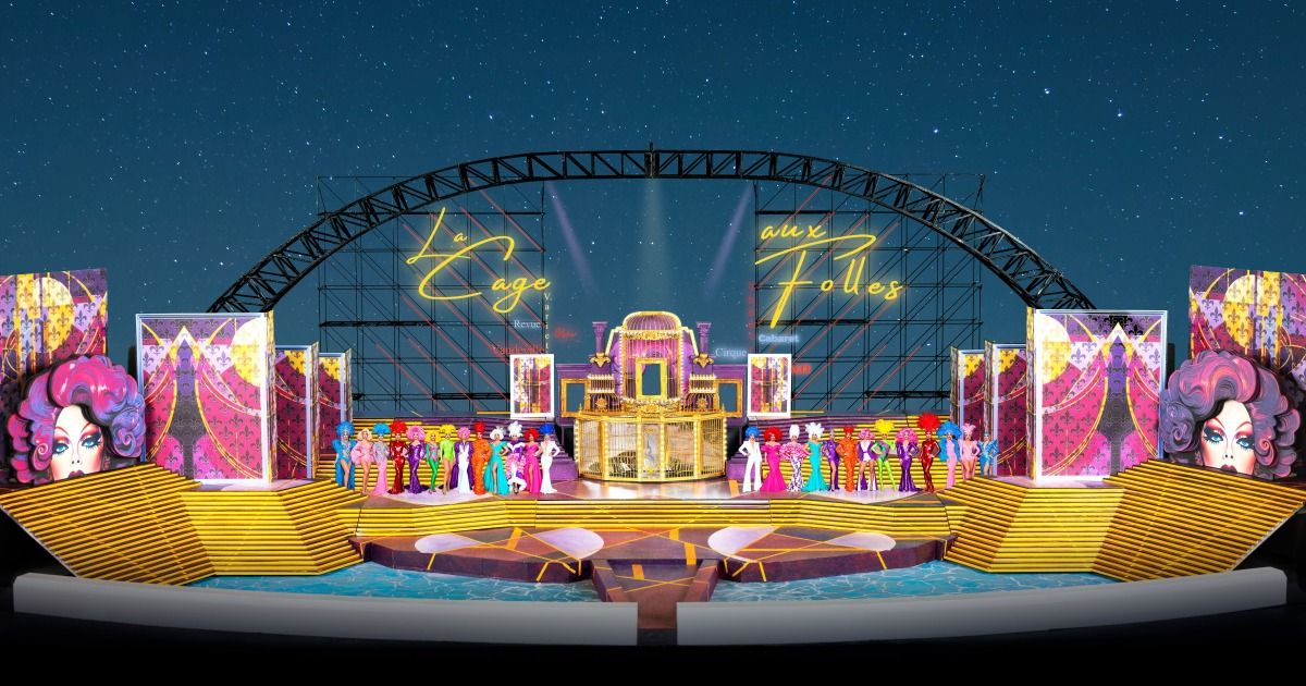 Eine aufwendige Bühnendekoration für eine Kabarettshow mit einem goldenen Käfig in der Mitte, farbenfrohen Darstellern und einer gewölbten Metallstruktur mit Neon-Schriftzügen.