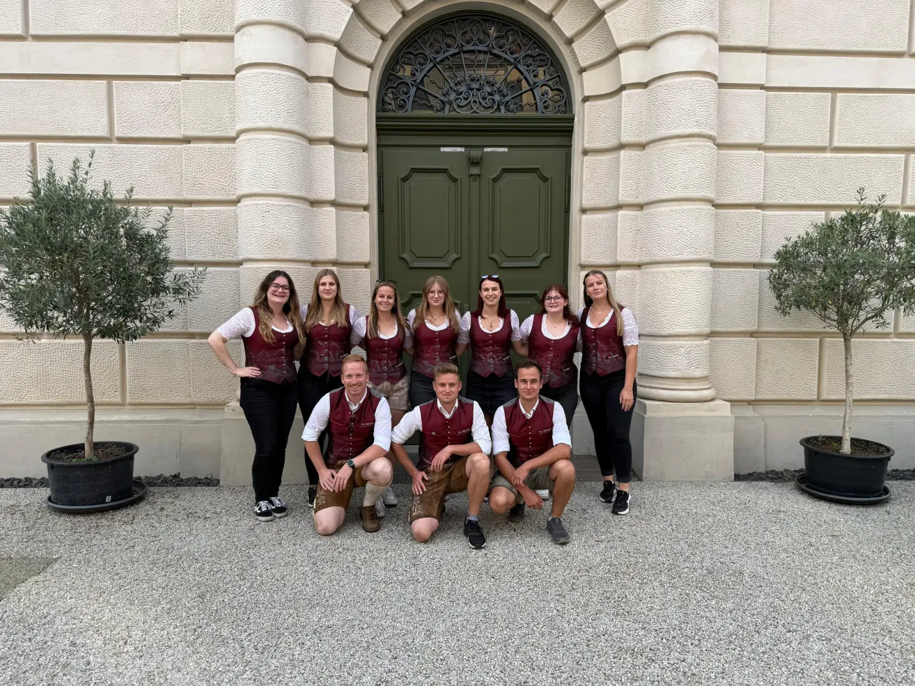 Eine Gruppe von Personen in traditioneller Kleidung posiert vor einem Gebäude mit einer grünen Tür.
