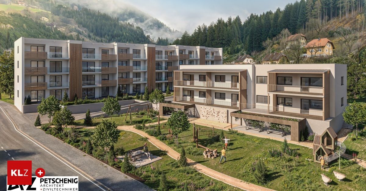 Ein Blick von oben auf ein modernes Apartmentgebäude mit einem Landschaftsgarten, mit Spielplatz, Bäumen und einem Weg. In der Ferne ein Berg mit Nebel.