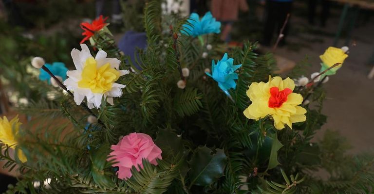Ein Nahaufnahme einer Blumenarrangement aus Papierblumen in verschiedenen Farben wie pink, gelb, weiß und blau.