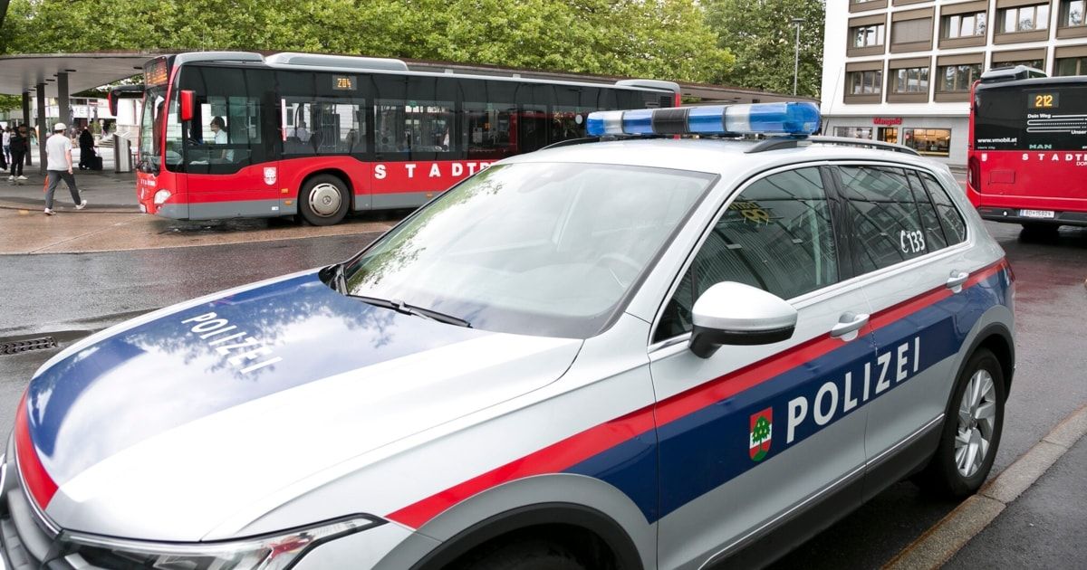 Ein Polizeiauto ist am Straßenrand geparkt, mit einem Bus im Hintergrund.