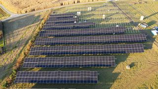 Eine Luftaufnahme eines großen Solarpanel-Feldes auf einem Feld mit einem nahegelegenen Weg.