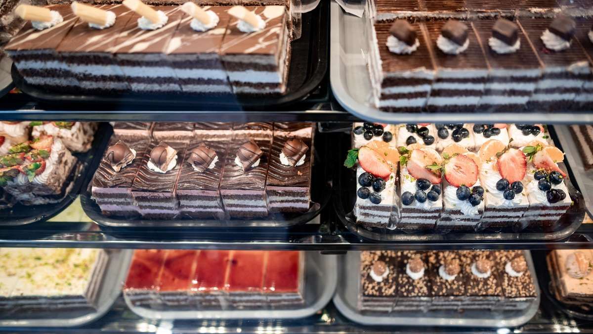 Eine Vitrine mit verschiedenen Desserts, darunter Schokoladenkuchen, Beeren-Törtchen und fruchtbedeckte Gebäcke.