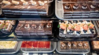 Eine Vitrine mit verschiedenen Desserts, darunter Schokoladenkuchen, Beeren-Törtchen und fruchtbedeckte Gebäcke.