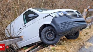 Ein silberner Volkswagen-Transporter ist zur Seite geneigt, wahrscheinlich nach einem Unfall. Das Vorderrad ist abgekoppelt, und das Fahrzeug befindet sich auf einem felsigen Gelände.
