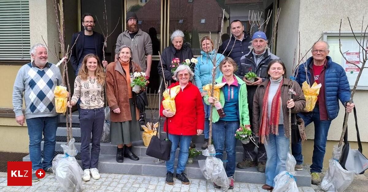 Eine Gruppe von Menschen steht auf den Stufen eines Gebäudes mit kleinen Bäumen in den Händen, einige mit Blumen und Blättern. Sie sind in Winterkleidung gekleidet.