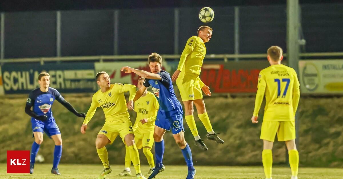 Fußballspieler in gelben und blauen Trikots sind auf dem Feld bei Nacht in Aktion. Ein Spieler in Gelb springt, um den Ball zu köpfen.