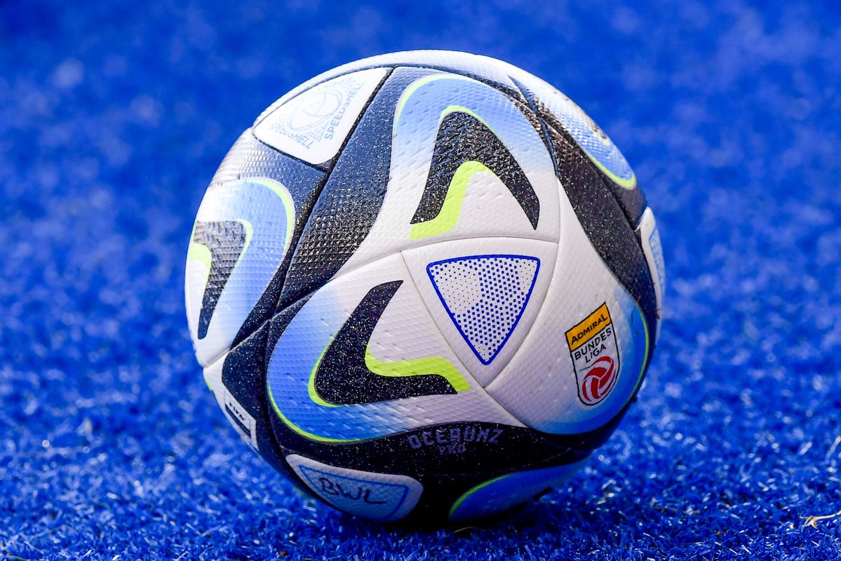 Ein Fußball mit blauen, weißen und schwarzen Farben mit dem Wort "Adidas" und einem Logo darauf. Er liegt auf einer blauen Oberfläche.