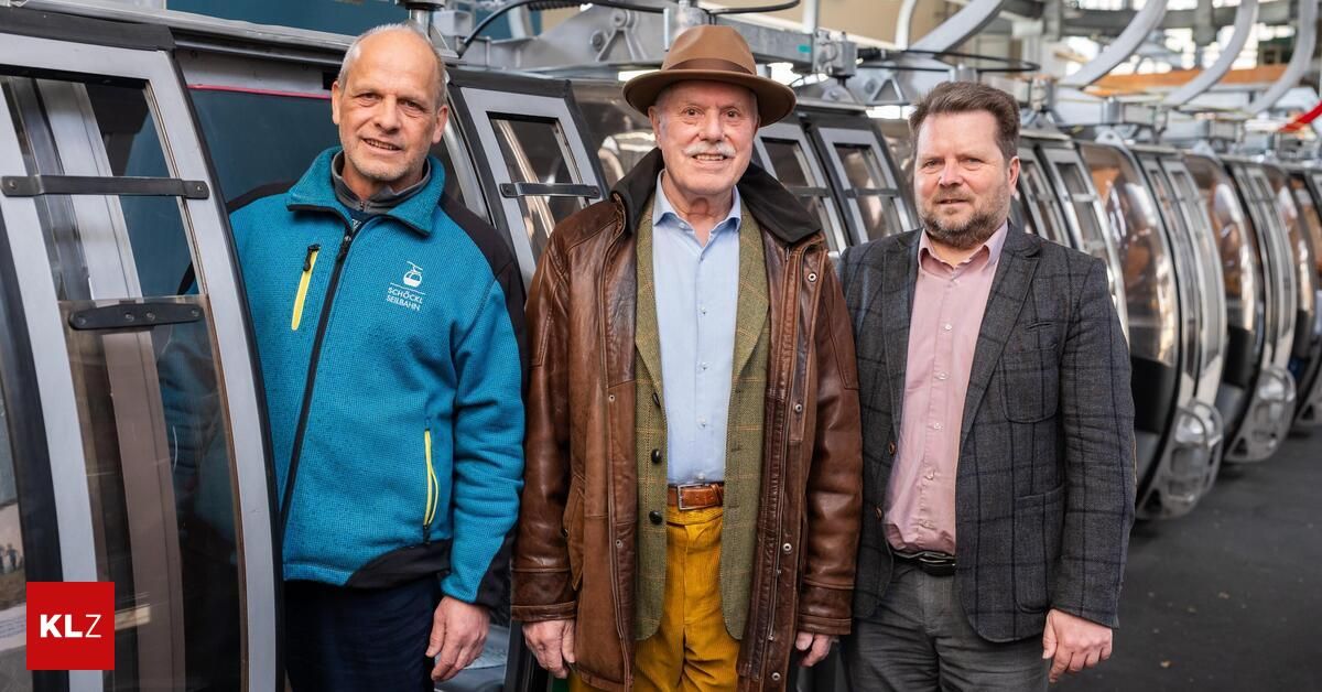 Drei Männer stehen nebeneinander in der Nähe einer Gondelbahn. Sie lächeln und scheinen für ein Foto zu posieren.