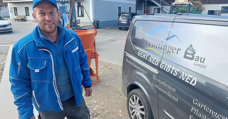 Ein Mann in einer blauen Jacke steht neben einem Van mit Fenninger-Dienstleistungen. Hinter ihm ist ein Maschinenfahrzeug und ein Gebäude.