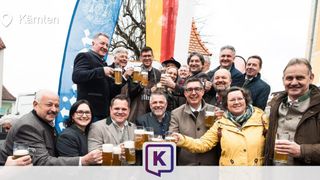 Eine Gruppe von Menschen mit Bierkrügen, lächelnd und posierend für ein Foto bei einer Outdoor-Veranstaltung.