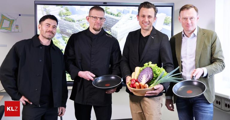 Four men are posing for a photo. One holds a frying pan, another holds a bowl of vegetables. Behind them, a screen displays a cityscape.