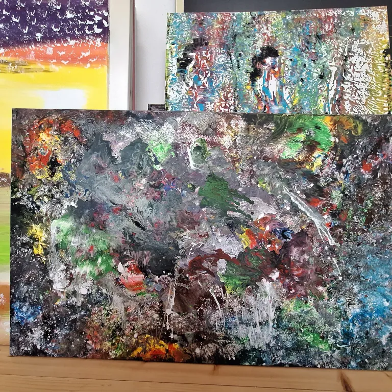 An abstract painting with vibrant colors and dynamic brush strokes occupies the forefront, surrounded by other artworks in the background.