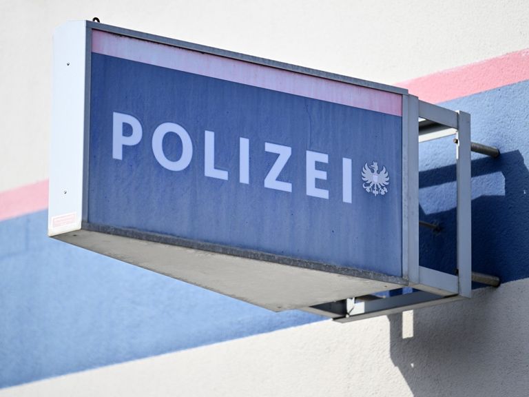 A blue sign with the word Polizei in white letters, featuring the German eagle emblem, is mounted on a building's wall.