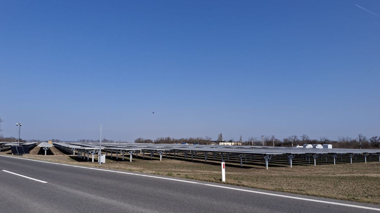 A highway with solar panels on the side, under a clear blue sky.
