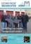 Eine Gruppe von Mitgliedern der Freiwilligen Feuerwehr steht vor einem Gebäude und hält ein repariertes Garagendach. Sie tragen alle Winterkleidung.