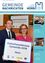 Ein Mann und eine Frau stehen vor einem Schild, auf dem Kulturfreundlicheste Gemeinde 2018 steht. Das Schild ist blau und weiß. Eine Museumseröffnung und ein Fest werden ebenfalls hervorgehoben.