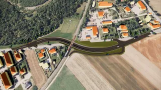 Aerial view of a suburban area with houses, farmland, and a road. There are many orange-roofed buildings and a long road. Vehicles are seen on the road.