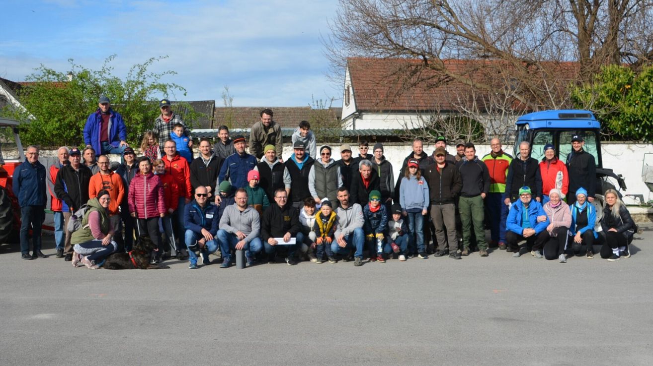 A group of people dressed in winter clothing are posing for a photo in front of a house with a brown roof.