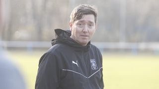 A man wearing a black jacket with a Puma logo and SCIESV ARNDORF text stands on a grassy field.