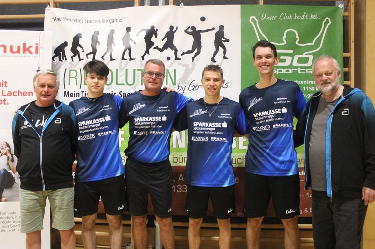 Five men in sports jerseys with the word 'SPARKASSE' on them pose for a photo. They are standing in front of a banner.