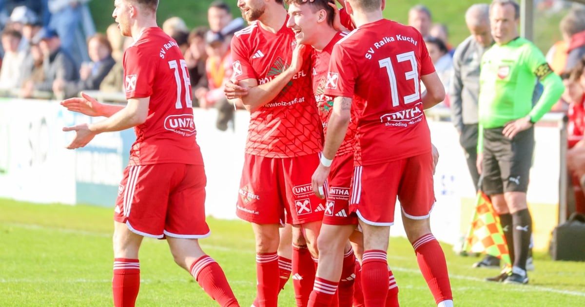 Soccer players in red uniforms are celebrating on a field with spectators in the background. The players wear numbers 7, 13, and 17 on their jerseys.