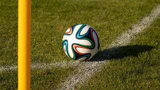 A soccer ball with multicolored patterns lies on a grassy field near a white line.