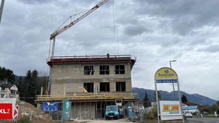A construction site with a crane, a building under construction, and a signboard reading Seeboden Am Unterrain.