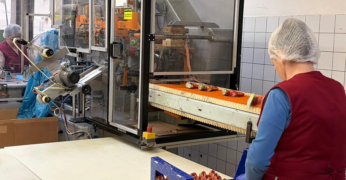 Eine Arbeiterin in einer Fabrik überwacht ein Förderbandsystem mit automatisierten Lebensmittelverpackungsmaschinen.