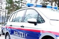 Ein Polizeifahrzeug mit roten und weißen Streifen ist am Straßenrand geparkt. Das Wort Polizei steht auf der Seite.