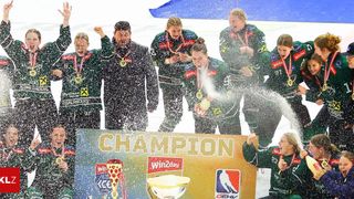 Eine Gruppe von Hockeyspielern feiert ihren Sieg, hält einen Pokal und sprüht Champagner. Das Schild sagt Champion.