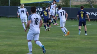 A soccer match with players in white and blue uniforms, number 18 jumps to head the ball. The background shows a banner with 'Ambulance' and a soccer ball in the air.