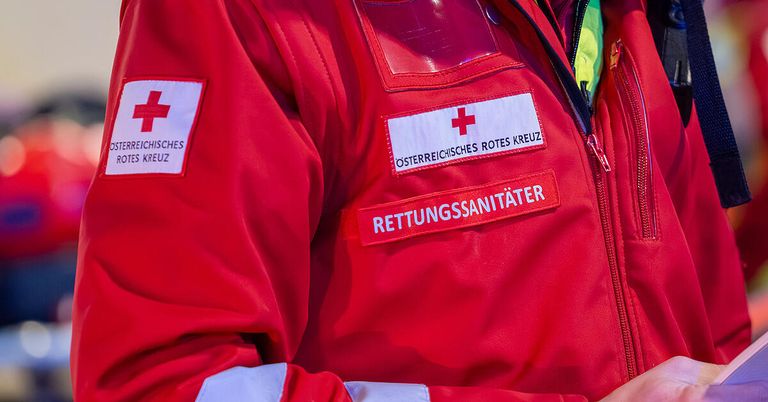 A red jacket with an Austrian Red Cross patch and the title Rettungssanitäter.