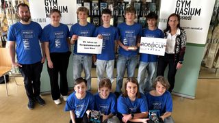 A group of young people in blue shirts pose for a photo. They are holding a sign that says they will go to the European Championship in Vienna.